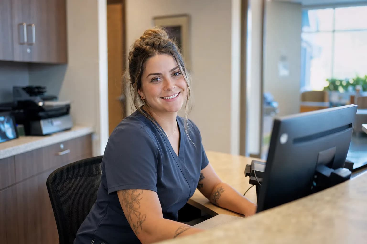 Friendly medical receptionist at a clinic front desk managing patient calls with Callbook AI